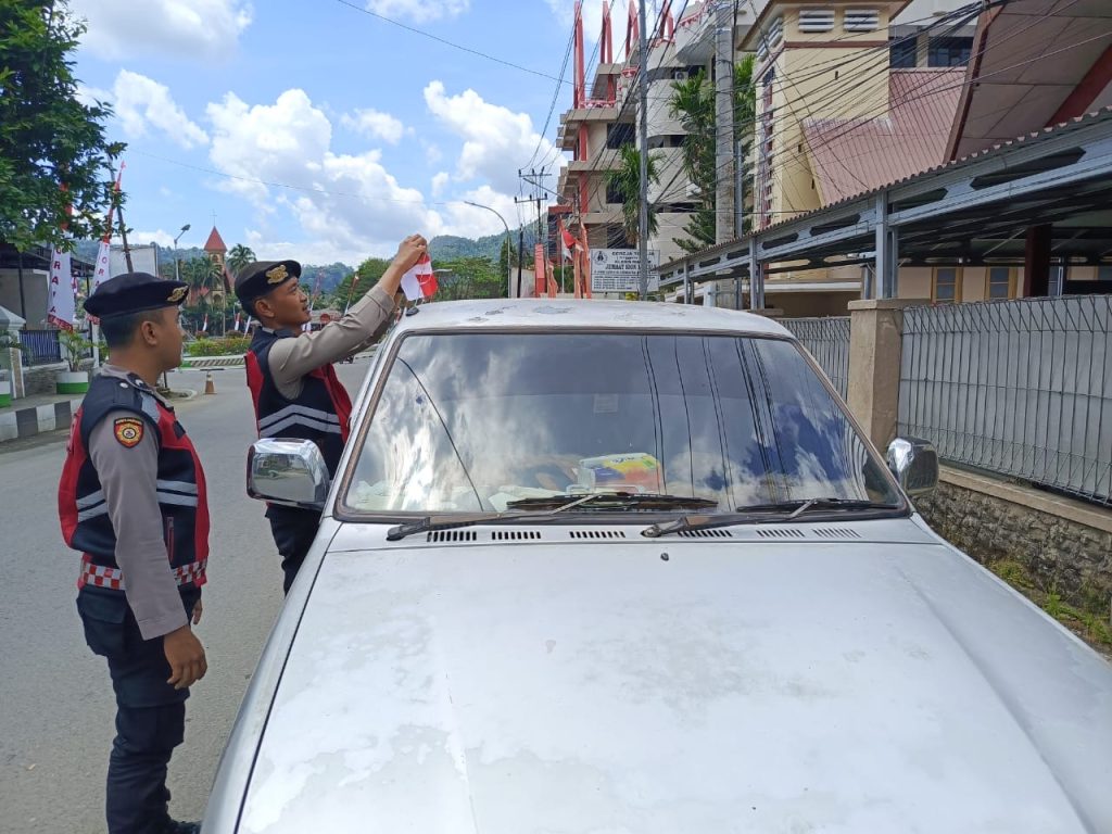 Personel Polres Tana Toraja Bagi Bendera Merah Putih ke Pengguna Jalan
