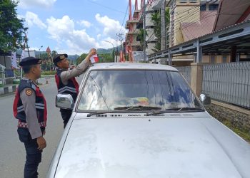 Personel Polres Tana Toraja Bagi Bendera Merah Putih ke Pengguna Jalan