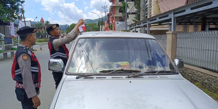 Personel Polres Tana Toraja Bagi Bendera Merah Putih ke Pengguna Jalan