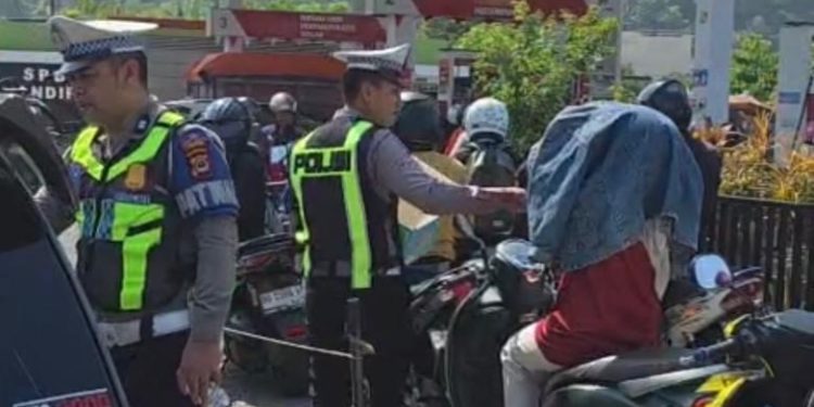 Personel Sat Lantas Polres Palopo Bagi Air Mineral ke Masyarakat Yang Antri BBM
